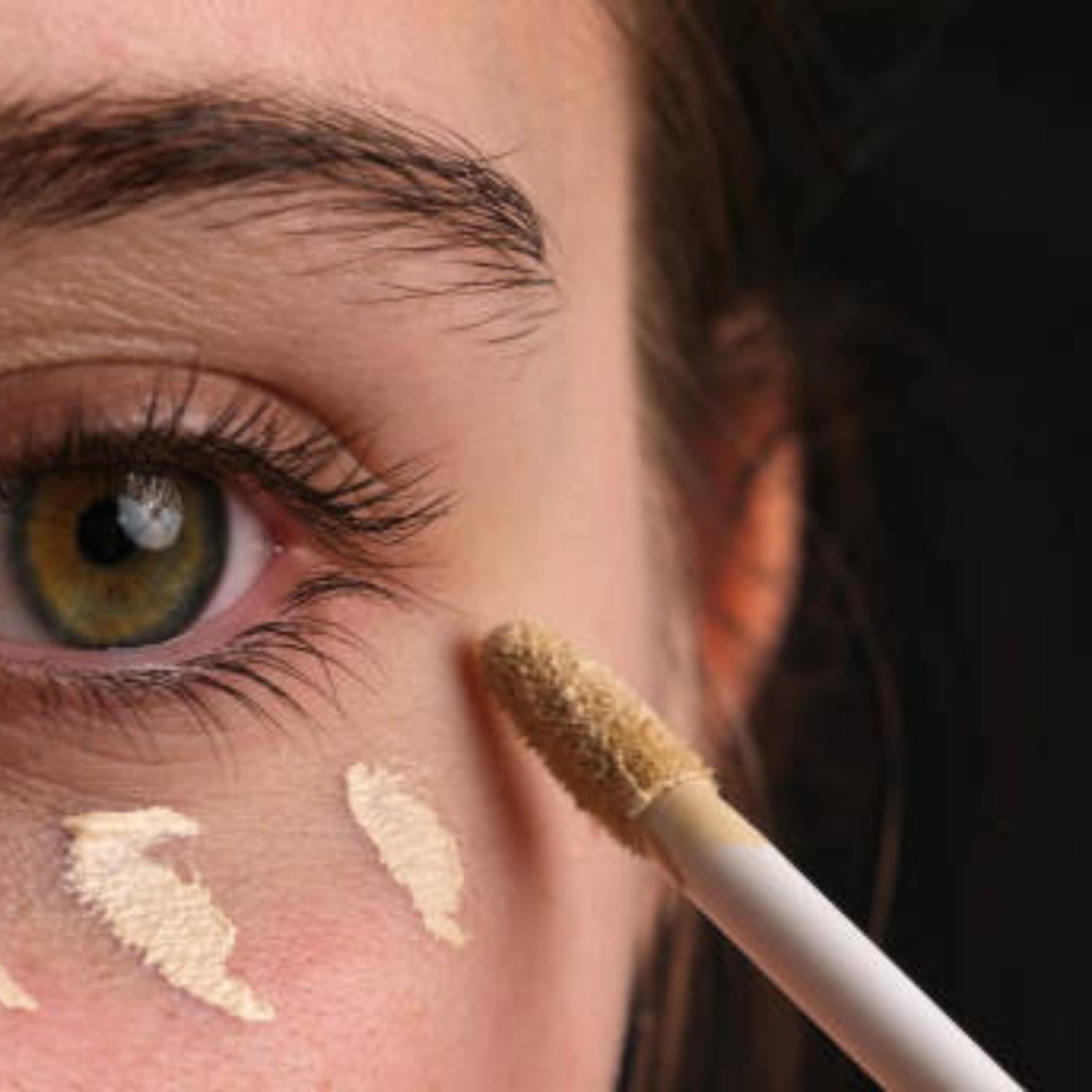 woman using eye concealer