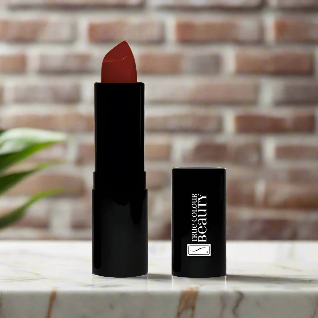 Daring Dahlia lipstick placed on a marble countertop, with its matte cream texture and bold hue standing out in the soft lighting