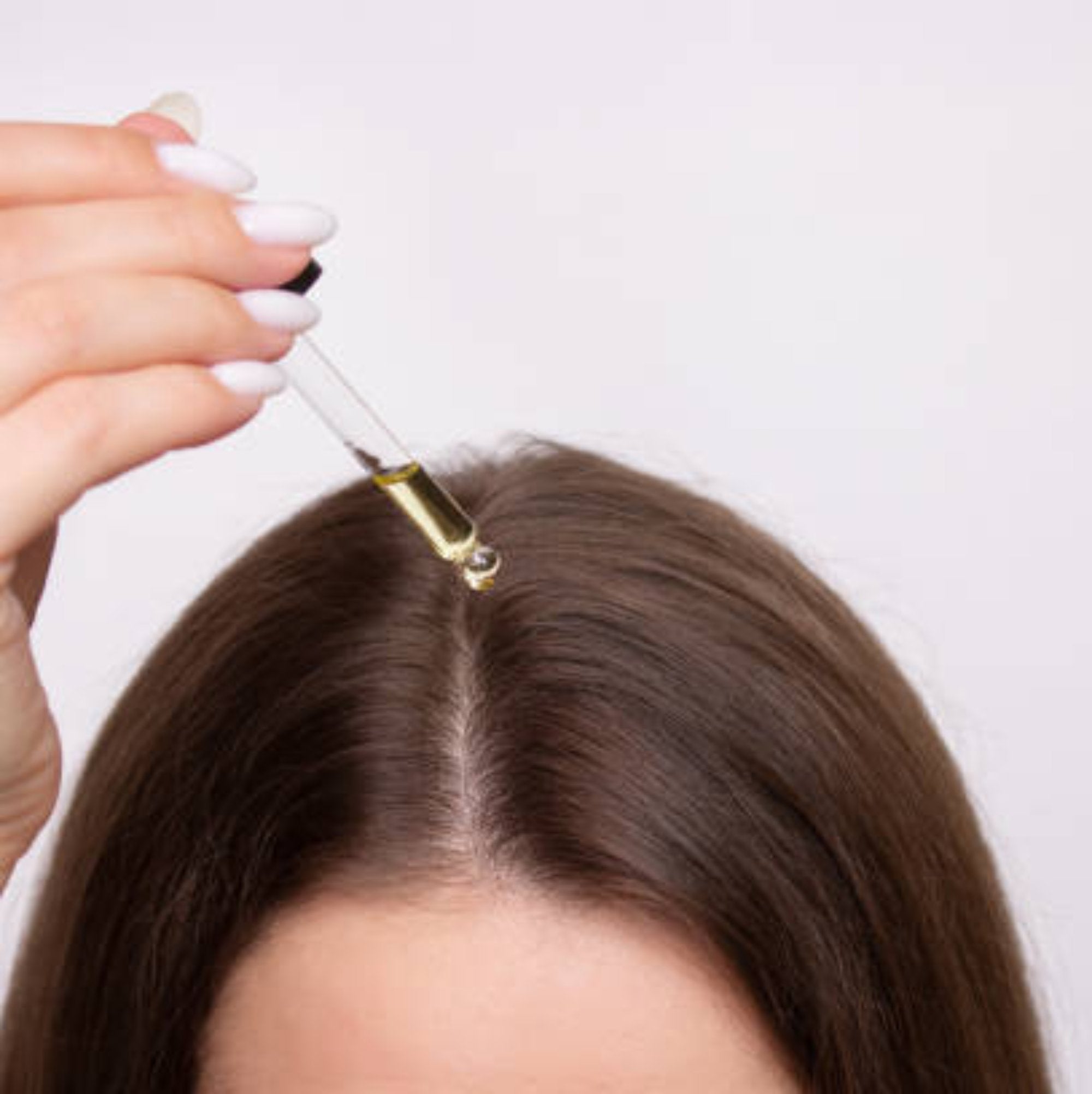 Model applying TCB Hair Growth Oil to her scalp and hair, demonstrating a nourishing treatment for healthier, fuller hair