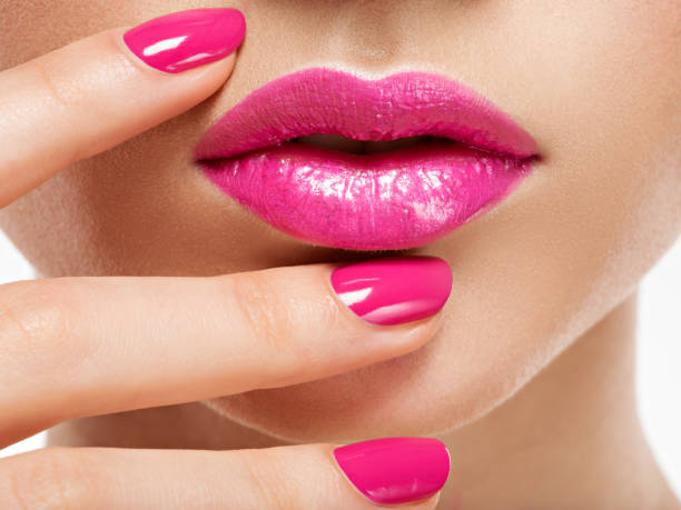 Closeup of pink lipstick and nail polish.